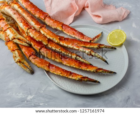 Luxury Kamchatka's Crab claw on gray plate with lemon slice and pink napkin at gray background