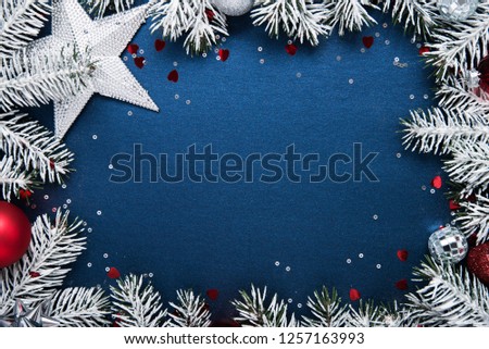 Merry Christmas and Happy Holidays greeting card, frame, banner. New Year. Noel. Christmas ornaments and fir tree on blue background top view. Winter holiday xmas theme. Flat lay.