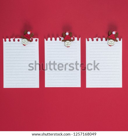  white blank sheet in a line torn out of notepad on a red background, close up