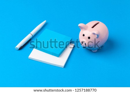 Piggy bank and notebook with a pen