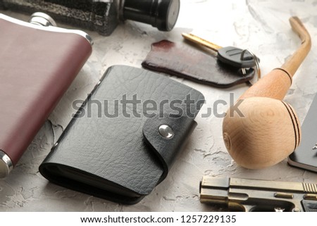 Men's Accessories. men's style. flask, business card holder, smoking pipe, keys on a light concrete background.