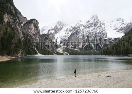 Lonesome woman near Lago di Braies - Pragser Wildsee, Dolomites, South Tyrol, Italy. Snowfall were minimal in northern regions of Italy that year and water level of lake was not high in May.