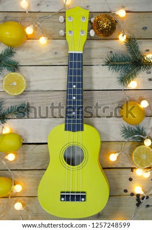 Photo of Guitar, Fresh Orange Lemon, Fir-tree branches, coffee beans and small light bulbs on Wooden Background. View from above.