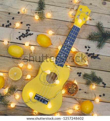 Photo shot, top view of Guitar, Fresh Orange Lemon, Fir-tree branches, coffee beans and small light bulbs on Wooden Background. 