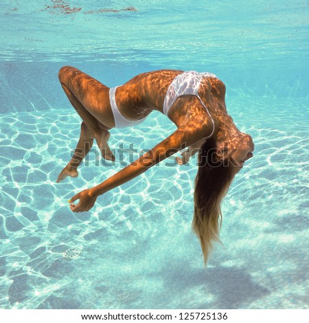 Girl portrait posing underwater with white bikini in swimming pool.