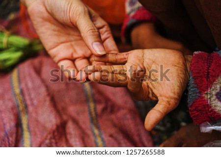 The woman hand touches the little girl’s dirty hand.