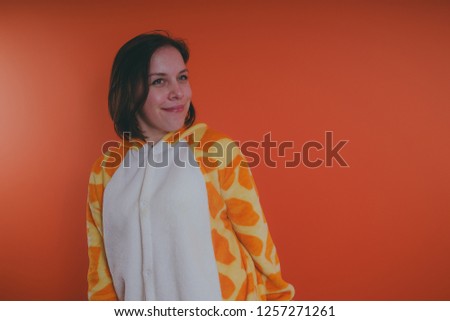 pajamas in the form of a giraffe. emotional portrait of a girls on an orange background. crazy and funny girl in a suit. animator for children's parties
