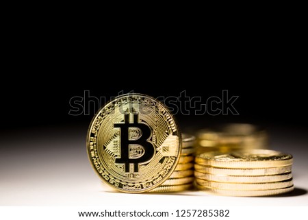 Gold Bitcoin Stacks with one Coin Full On, White to Black Gradient Background Royalty-Free Stock Photo #1257285382