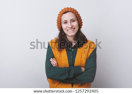 Young hipster girl smiling and looking at camera yaring yellow hat on white background.