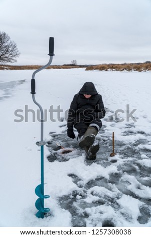 A fisherman catches a fish on winter fishing