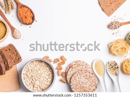Different types of high carbohydrate food. Flour, bread, dry pasta and lentils and other ingredients on the white background. Royalty-Free Stock Photo #1257353611