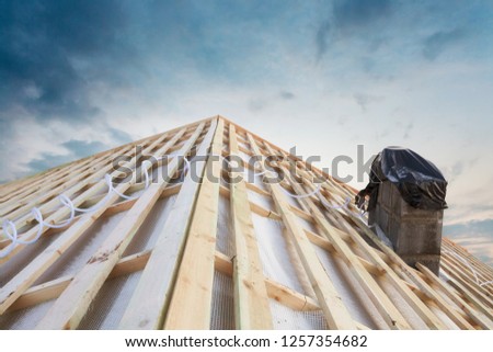 Photo of brand new triangular wooden roof with covered furnace against on beautiful serenity blue sky