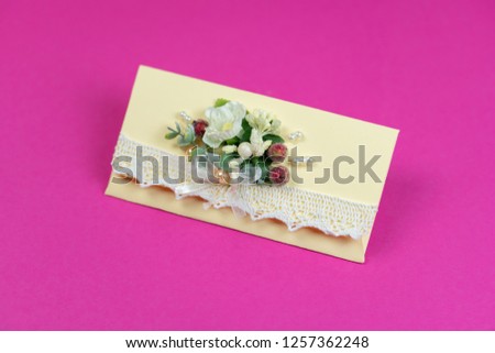 Vintage congratulatory envelope. Made of craft paper with a decorative flower. On a pink background.