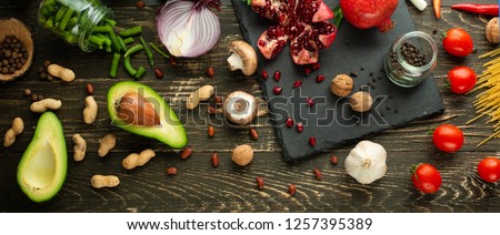 Healthy vegan food cooking ingredients. Flat lay vegetables, fruits, avocados, nuts, mushrooms, onions, green beans and broccoli and greens on a wooden background, top view. Pure food, diet concept