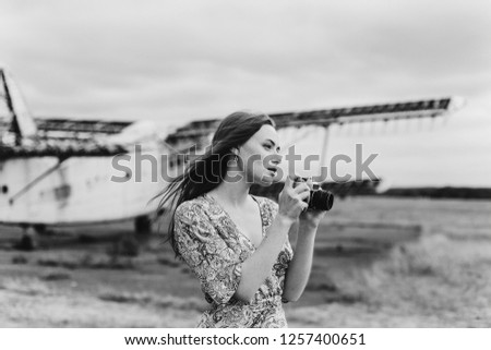 Close up black and white portrait of young beautiful stylish hipster  girl taking photos outdoors near airplane. Girl with freckles on body taking pictures with photo camera. Black and white photoshot