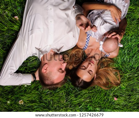 happy parents with newborn baby laying on the green grass