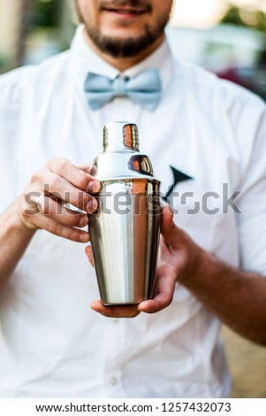 Cocktail steel shaker shaker in hands of the bartender. Barman equipment. Barman in a bow tie makes a cocktail. Royalty-Free Stock Photo #1257432073