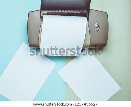 A printer with blank paper forms on a colored pastel background. Top view, flat lay.