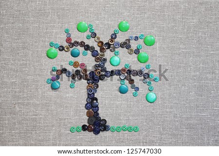 Tree with green fruit composed of the buttons on gray background of textile