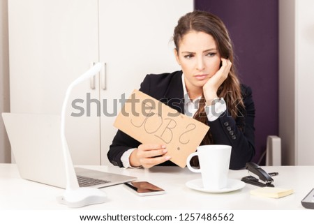 Woman in business dress in office holds job sign lost her job unemployment