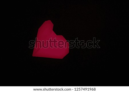 A red color origami heart on a black background