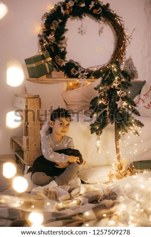 Beautiful baby girl near a Christmas tree with gifts with little boy feeding black vietnamese piglet. Concept of the Chinese New Year 2019 of the Pig