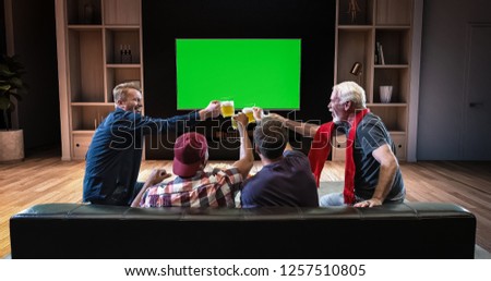 A group of fans is watching a TV and celebrating some joyful sports moment, sitting on the couch in the living room. The living room is made in 3D. TV is green screen for further editing.