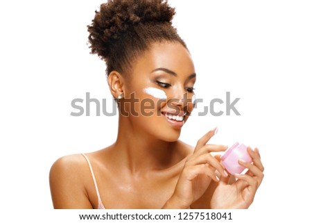 Аttractive girl using moisturizing cream. Photo of smiling african american girl on white background. Beauty & Skin care concept