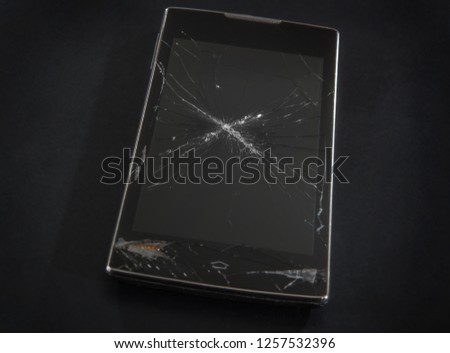 Smartphone with a broken cracked display on a dark background close-up