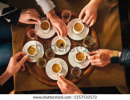 Group of people with henna mehndi tattoo on the hands drinking turkish coffey, top view