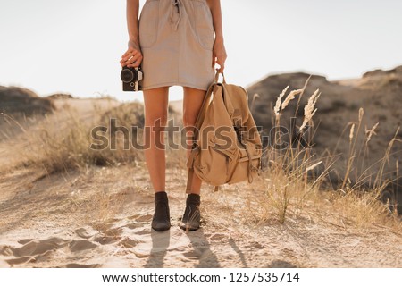 close up legs in shoes, fashion details of stylish woman in khaki dress in desert, traveling in Africa on safari, wearing boots, holding backpack, photo camera, exploring nature, summer, footwear