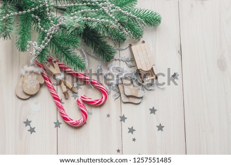 Wooden Christmas decorations on a white wooden background with a branch of a Christmas tree and red caramel candy space for text