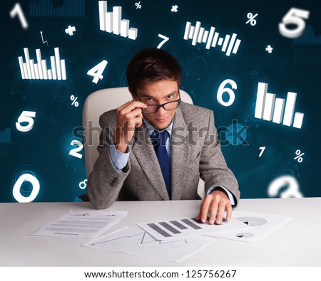 Young businessman sitting at desk with diagrams and statistics