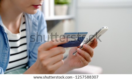 close up portrait of young housewife shopping online on boxing day in christmas sale. lady holding credit card and cellphone doing internet payment e commerce. focus photo on debit white smart phone