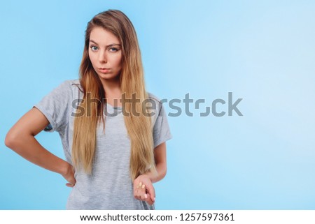 Girl in gray t-shirt and blue jeans looks suspicious. Concept of unpleasant communication with opponent, poor service is not true for clients. Copy space right. Closeup.