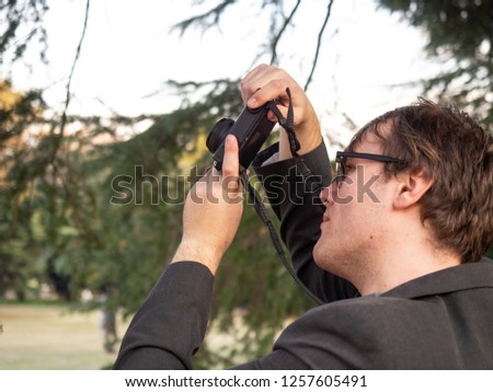 A man taking pictures in the park on his compact digital camera