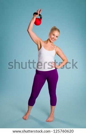 Fitness girl poses with a kettlebell, blue background