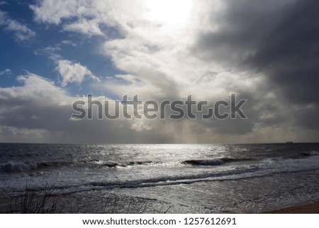Gentle waves rolling in at  Ocean Beach Bunbury Western Australia on a cloudy afternoon in early autumn create a scenic sea scape with an ominous cumulonimbus sky.