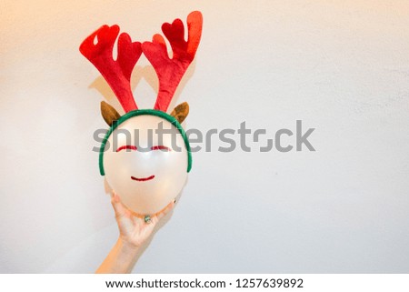 Hand holding a balloon wearing a Christmas hat.