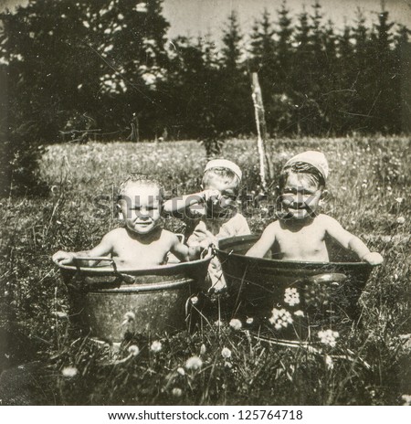 Vintage photo of little children bathing in wash tubs outdoor (early fifties)