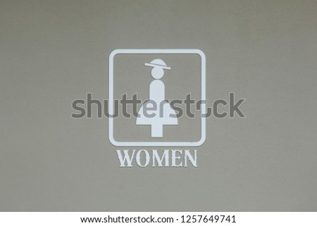 white woman's toilet symbol on a gray cement wall.