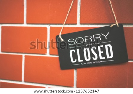 Close sign hanging on brown stone wall texture background. Business and service concept.