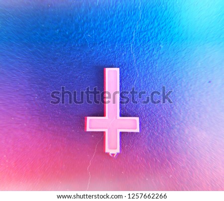 Upside down cross on a psychedelic colored wall. 