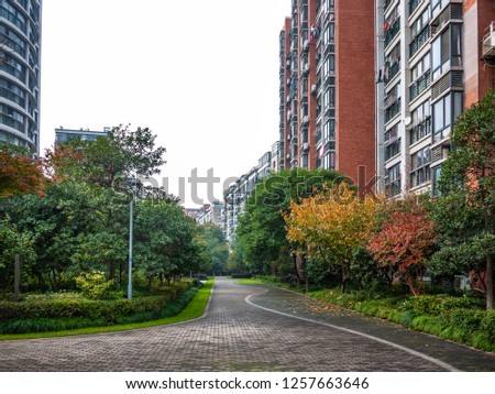 Flat stone pedestrian walkway in an inner courtyard garden with green trees and grass between high-density residential apartment buildings. Ningbo, Zhejiang Province, China.