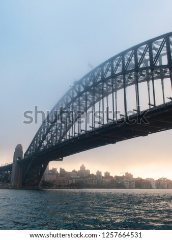 Sydney Harbour Bridge view under sunrise light and fog.
