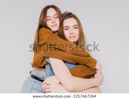 Two sisters twins beautiful girls hipsters in casual clothing on grey background isolated, concept love, friendship, soul mates