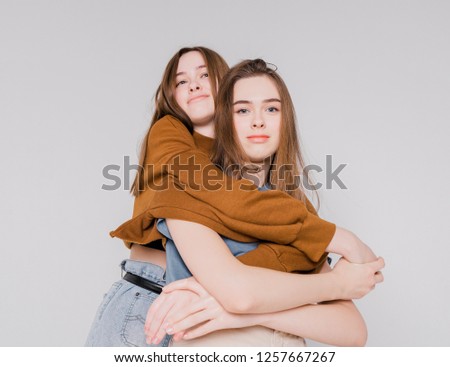 Two sisters twins beautiful girls hipsters in casual clothing on grey background isolated, concept love, friendship, soul mates