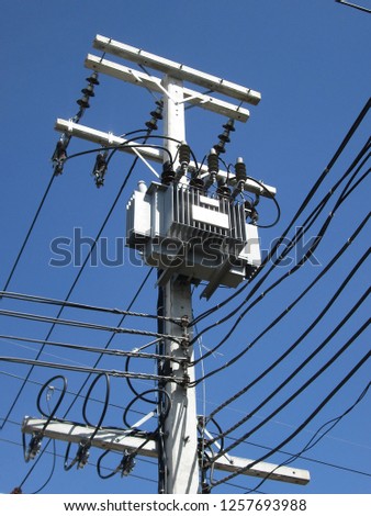 Outdoor transformer mounted on pole. For high voltage and low voltage switching to the user. On the blue sky.