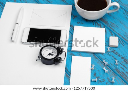 Branding stationery mockup on blue desk. Top view of paper, business card, pad, pens and coffee.