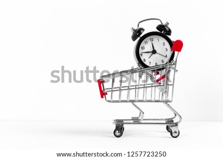 Small shopping cart with alarm clock. Shopping time concept